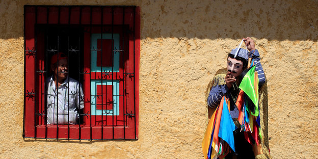 Eine maskierte Person steht vor einer Hauswand