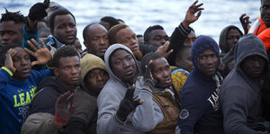 Dicht gedrängt sitzen Flüchtlinge zusammengepfercht auf einem Boot