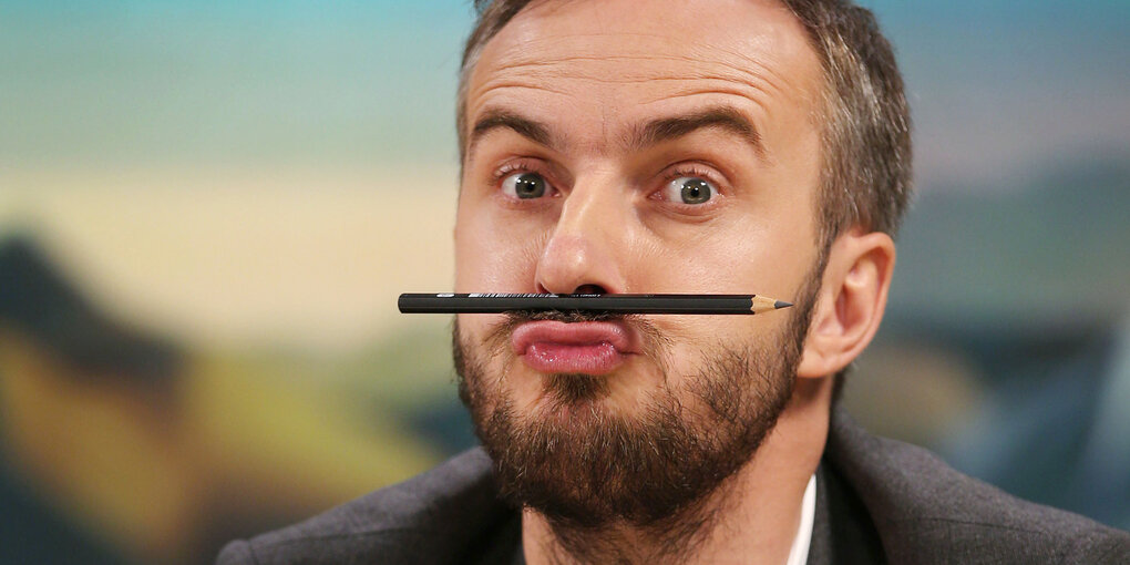 Jan Böhmermann balanciert einen schwarzen Stift auf seiner Oberlippe