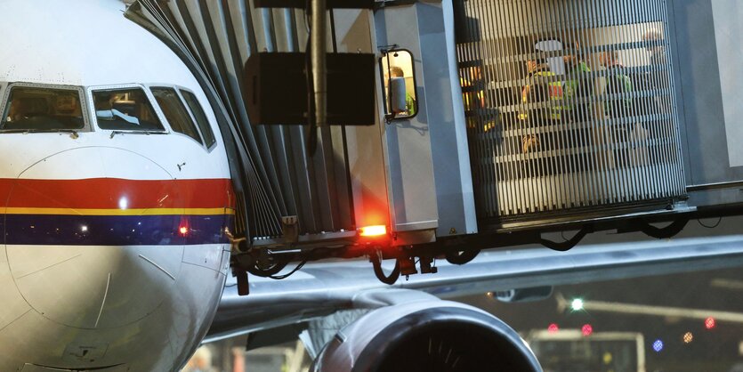 Ein Flugzeug auf einem abendlichen Flughafen - mit Gangway, durch die Polizisten gehen.