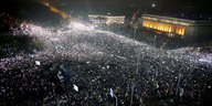 Aus der Vogelperspektive: eine riesengroße Menschenmenge auf einem städtischen Platz, abends