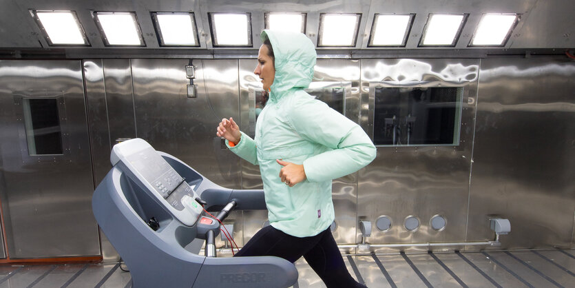 Eine Frau auf einem Laufband testet Outdoorkleidung