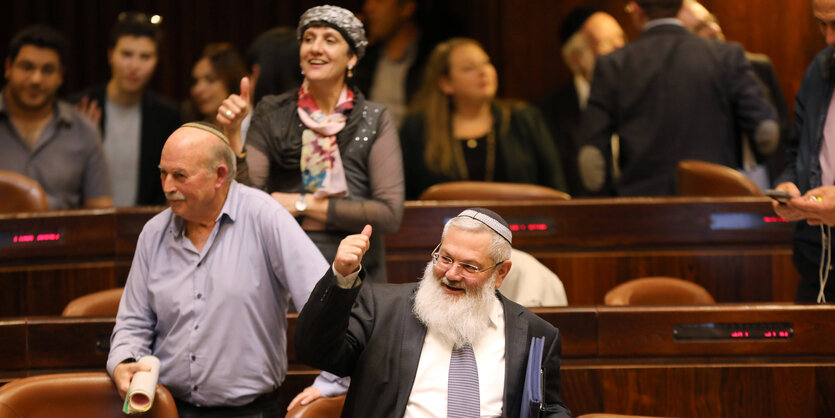 Menschen in einem Saal zeigen ihre Daumen