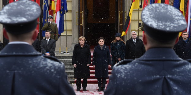 Merkel und Szydło auf einem roten Teppich, davor Uniformierte