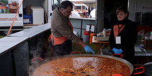 Zwei Leute vor einer großen Pfanne Paella