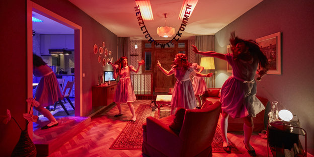 Mädchen in Kinderkleidchen rocken das in rotem Licht badende Wohnzimmer