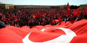 Menschen mit türkischen FAghnen vor einer riesigen Fahne