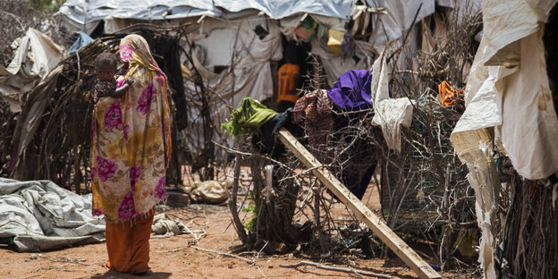 Eine Frau mit Kind steht neben einer Hütte im Flüchtlingslager Dadaab