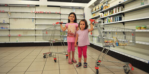 Zwei Mädchen in rosa Leggind und rosa T-Shirts stehen in einem Supermarkt, jede hat einen Einkaufswagen an der Hand