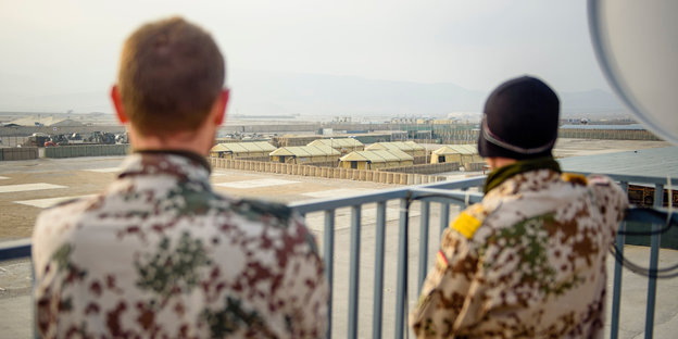 Zwei Bundeswehrsoldaten schauen von einer Terrasse über das Feldlager Camp Marmal in Masar-i-Scharif