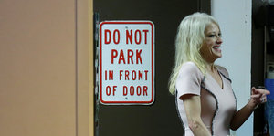 Kellyanne Conway steht lachend neben einem Schild mit der Aufschrift „Do Not Park“