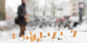 Zigarettenstummel stecken im Schnee