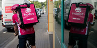 Ein Foodora-Lieferant mit Rucksack fährt Rad. Er spiegelt sich in einem Schaufenster