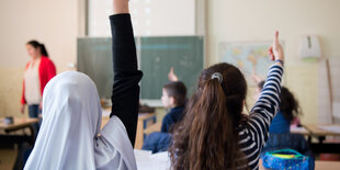 Zwei Mädchen zeigen in der Schule auf