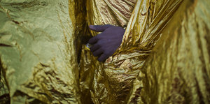 Eine Hand eines Flüchtlings guckt unter einer Wärmedecke hervor