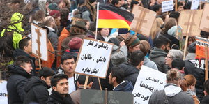 Demonstranten in Düsseldorf halten Schilder in arabischer Schrift hoch. Zentral im Bild ist eine Deutschlandfahne