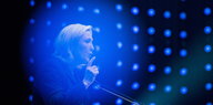 eine Frau in blauem Licht vor einem Mikofon