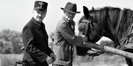 zwei Männer die skeptisch gucken, daneben ein Pferd