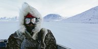 eine Frau mir Skibrille und einem dicken Anorak in arktischer Landschaft