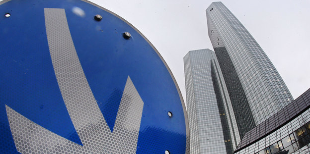 Der Pfeil eines Straßenschilds zeigt steil nach unten, im Hintergrund das Hauptquartier der Deutschen Bank