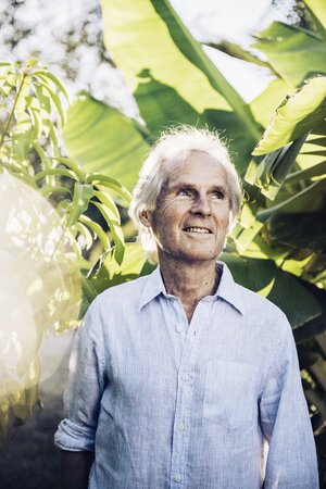 Friedrich Lehmann steht im Garten vor einer Pflanze mit großen Blättern Friedrich Lehmann steht im Garten vor einer Pflanze mit großen Blättern