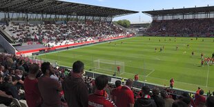 Stadion mit Zuschauern auf Rängen, Fußballspieler auf dem Rasen