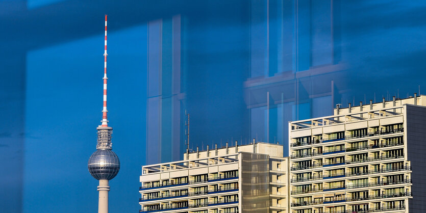 Die Wohnblöcke neben dem Berliner Fernsehturm, beide heben sich hell gegen den strahlend blauen Himmel ab