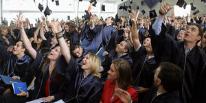Studierende werfen nach dem Bachelorabschluss ihre Hüte in Luft