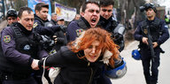 Junge Frau wird von mehreren Polizisten festgehalten