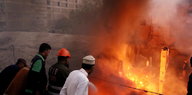 In Karachi brennt ein Medikamenten-Depot lichterloh, Menschen stehen ratlos daneben