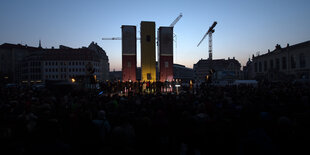 Menschen haben sich auf dem Neumarkt in Dresden (Sachsen) vor dem Kunstwerk «Monument» des syrischen Künstlers Manaf Halbouni versammelt.