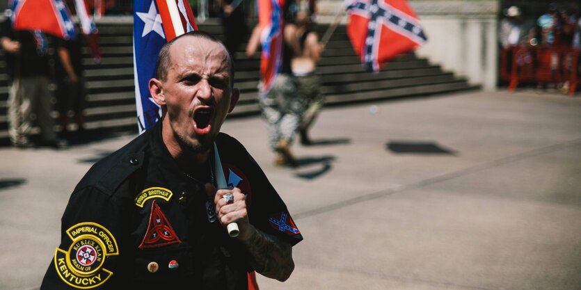 Ein brüllender Mann hält eine Flagge über seine Schulter