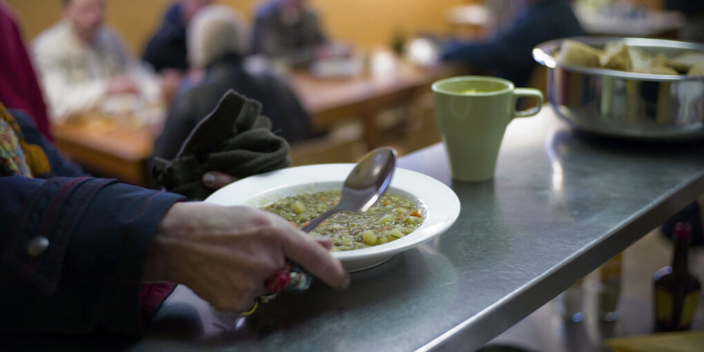 Jemand fässt einen Teller Suppe an