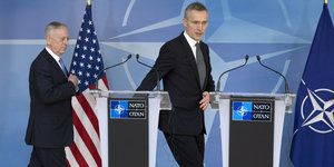 Nato-Generalsekretär Jens Stoltenberg (r) und US-Verteidigungsminister James Mattis schreiten auf zwei Rednerpulte zu, im Hintergrund die US- und die Nato-Flagge