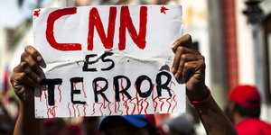 Ein Mann hält ein Schild hoch. Auf dem steht: CNN ist Terror auf Spanisch