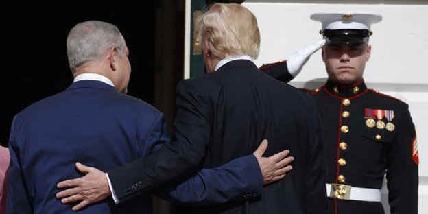 Benjamin Netanjahu und Donald Trump haben die Arme hintern den Rücken des je anderen gelegt. Man sieht sie von hinten