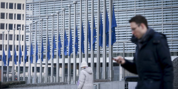 Ein Mann schaut auf sein Handy und läuft am EU-Parlament vorbei