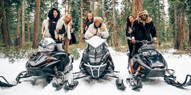 Die drei Rapper von Migos posieren mit Frauen und Skibobs im Schnee