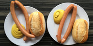 Zwei Paar Wiener Würstchen mit Senf und Brot liegen auf einem Teller