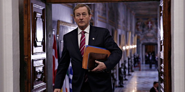Der irische Premier Enda Kenny geht mit einem Ordner unterm Arm durch eine Tür