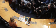 Angela Merkel sitzt an einem Tisch, ihr gegenüber steht eine Gruppe Journalisten