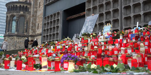 Kerzen und Blumen liegen vor einer Kirche