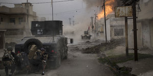 Ein irakischer Panzer in den zerstörten Straßen von Mossul, am Ende der Straße sind Flammen zu sehen