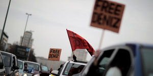 Menschen halten "Free Deniz"-Schilder aus den Autofenstern