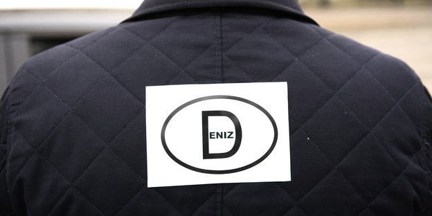 Ein Mann hat einen Aufkleber mit dem Länderkennzeichen «D» und dem Schriftzug «Deniz» steht am 19.02.2017 in Berlin ebi einem Autokorso auf der Straße
