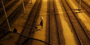 Menschen laufen nachts auf Bahnschienen