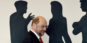 Martin Schulz im Vordergrund, Schatten vondrei gestikulierenden Menschen im Hintergrund