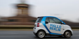 Ein kleines Auto der Firma car2go fährt an der Siegessäule in Berlin vorbei