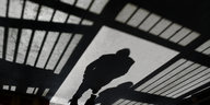 Der Schatten einer Zellenwand und eines Inhaftierten auf Beton