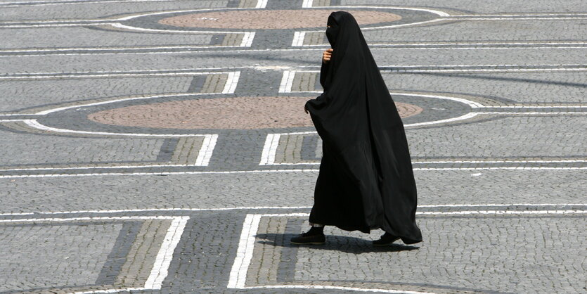 Vollverschleierte Frau geht über Platz